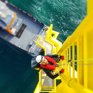 Manual high worker offshore climbing on wind-turbine on ladder. GWO Basic Safety Training